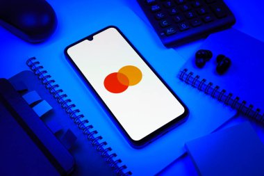 Prag, Çek Cumhuriyeti - 08 18 2025: Merkezde Mastercard logosu sergilenen bir cep telefonu ile ofis malzemeleri düzenlemesi. Mastercard ödeme kartları ve hizmetler sağlayan bir finans şirketidir..