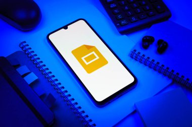 Prag, Çek Cumhuriyeti - 08 18 2025: Merkezde Google Slides logosunu gösteren bir cep telefonu ile ofis malzemeleri düzenlemesi. Google Slides sunumlar ve slayt gösterileri oluşturmak için bir platformdur.