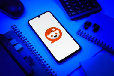 Prag, Çek Cumhuriyeti - 08 18 2025: Merkezde Reddit logosunu gösteren bir cep telefonu ile ofis malzemeleri düzenlemesi. Reddit tartışma, haber ve toplum içeriği için bir platformdur.