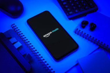Prag, Çek Cumhuriyeti - 08 18 2025: Merkezde Amazon Müzik logosu sergilenen bir cep telefonu ile ofis malzemeleri düzenlemesi. Amazon Müzik müzik müzik için bir platformdur..