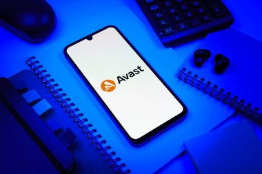 Prag, Çek Cumhuriyeti - 08 18 2025: Avast logosunu gösteren bir cep telefonu ile ofis malzemeleri düzenlemesi. Avast antivirüs ve siber güvenlik için bir platformdur.