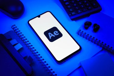 Prag, Çek Cumhuriyeti - 08 18 2025: Ofis malzemelerinin merkezde After Effects logosu sergilenen bir cep telefonu ile düzenlenmesi. After Effects hareket grafikleri ve görsel efektler için bir yazılımdır..