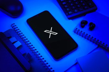 Prag, Çek Cumhuriyeti - 08 18 2025: Merkezinde X logosu sergilenen bir cep telefonu ile ofis malzemeleri düzenlemesi. X, kısa gönderileri ve güncellemeleri paylaşmak için bir platformdur.