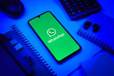Prag, Çek Cumhuriyeti - 08 18 2025: Ofis malzemelerinin merkezde WhatsApp logosunu gösteren bir cep telefonu ile düzenlenmesi. WhatsApp mesaj, çağrı ve medya göndermek için bir uygulamadır.