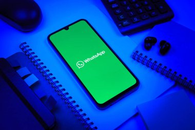 Prag, Çek Cumhuriyeti - 08 18 2025: Ofis malzemelerinin merkezde WhatsApp logosunu gösteren bir cep telefonu ile düzenlenmesi. WhatsApp mesaj, çağrı ve medya göndermek için bir uygulamadır.