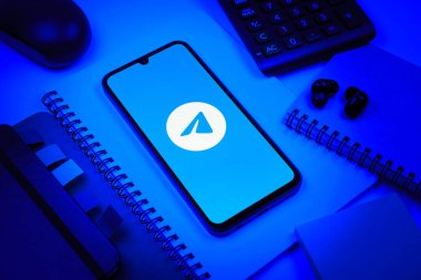 Prag, Çek Cumhuriyeti - 08 18 2025: Merkezde Telegram logosunu gösteren bir cep telefonu ile ofis malzemeleri düzenlemesi. Telgraf hızlı ve güvenli iletiler için bir uygulamadır.