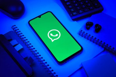 Prag, Çek Cumhuriyeti - 08 18 2025: Ofis malzemelerinin merkezde WhatsApp logosunu gösteren bir cep telefonu ile düzenlenmesi. WhatsApp mesaj, çağrı ve medya göndermek için bir uygulamadır.