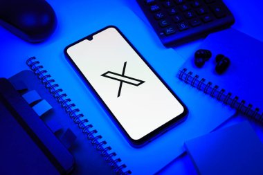 Prag, Çek Cumhuriyeti - 08 18 2025: Merkezinde X logosu sergilenen bir cep telefonu ile ofis malzemeleri düzenlemesi. X, kısa gönderileri ve güncellemeleri paylaşmak için bir platformdur.