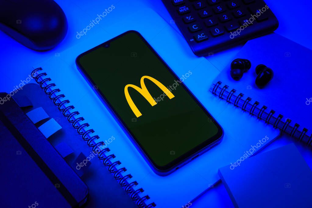 Prague, Czechia - 08 18 2025: An arrangement of office supplies with a mobile phone in the center displaying McDonalds logo. McDonalds is a fast-food chain serving burgers, fries, and more.