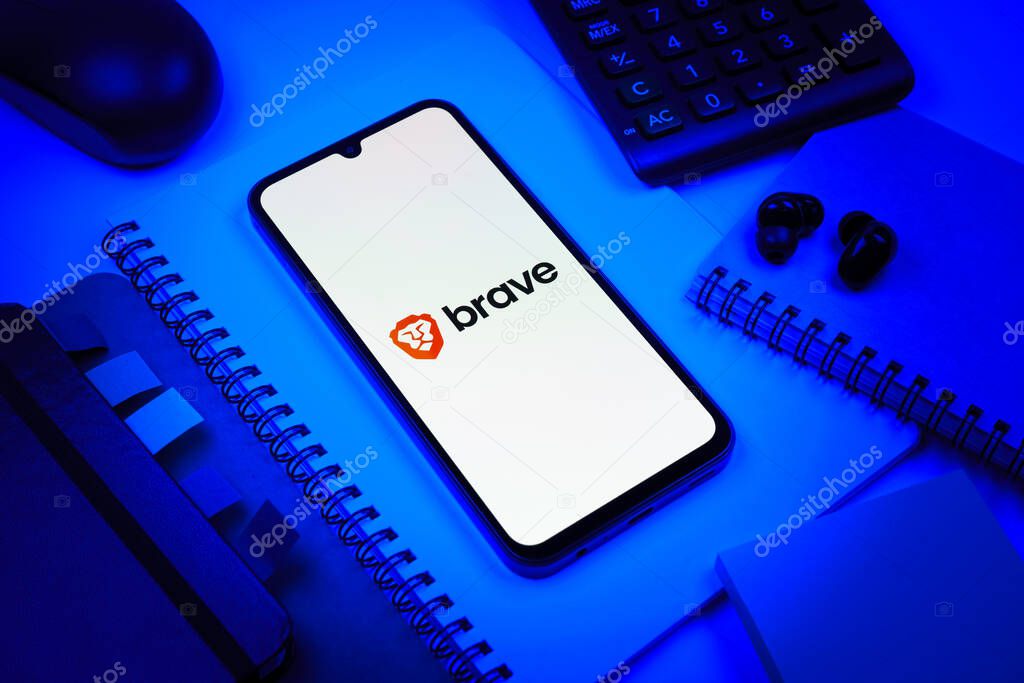 Prague, Czechia - 08 18 2025: An arrangement of office supplies with a mobile phone in the center displaying Brave logo. Brave is a web browser focused on privacy and speed.