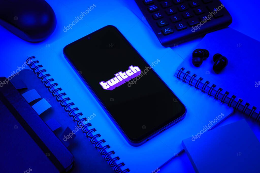 Prague, Czechia - 08 18 2025: An arrangement of office supplies with a mobile phone in the center displaying Twitch logo. Twitch is a platform for live streaming games and content.