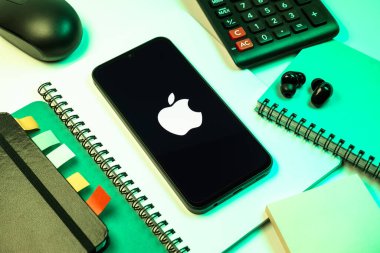 Prag, Çek Cumhuriyeti - 08 18 2025: Merkezi Apple logosunu gösteren bir cep telefonu ile ofis malzemeleri düzenlemesi. Apple iPhone, bilgisayar ve hizmet üreten bir teknoloji şirketidir..
