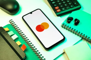 Prag, Çek Cumhuriyeti - 08 18 2025: Merkezde Mastercard logosu sergilenen bir cep telefonu ile ofis malzemeleri düzenlemesi. Mastercard ödeme kartları ve hizmetler sağlayan bir finans şirketidir..