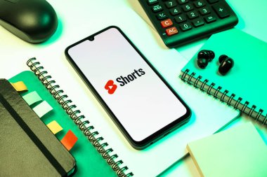 Prag, Çek Cumhuriyeti - 08 18 2025: Merkezde Youtube Shorts logosunu gösteren bir cep telefonu ile ofis malzemeleri düzenlemesi. Youtube Shorts kısa form video içeriği için bir platformdur.