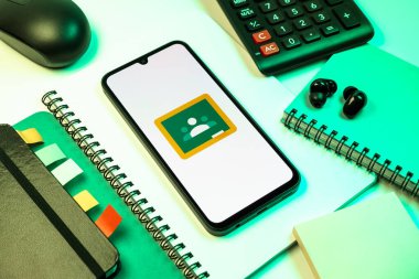 Prag, Çek Cumhuriyeti - 08 18 2025: Merkezde Google Sınıfı logosunu gösteren bir cep telefonu ile ofis malzemeleri düzenlemesi. Google Sınıfı, sınıfları ve eğitim içeriğini yönetmek için bir platformdur.