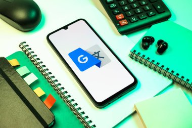 Prag, Çek Cumhuriyeti - 08 18 2025: Merkezde Google Translate logosunu gösteren bir cep telefonu ile ofis malzemeleri düzenlemesi. Google Çevirisi metni ve konuşmayı diller arası çevirmek için bir platformdur..