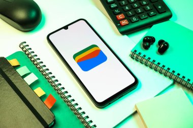 Prag, Çek Cumhuriyeti - 08 18 2025: Merkezde Google Cüzdan logosunu gösteren bir cep telefonu ile ofis malzemeleri düzenlemesi. Google Cüzdanı dijital ödeme yöntemlerini depolamak ve kullanmak için bir platformdur.