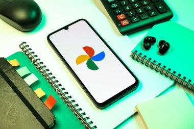 Prag, Çek Cumhuriyeti - 08 18 2025: Merkezde Google Photos logosunu gösteren bir cep telefonu ile ofis malzemeleri düzenlemesi. Google Fotoğrafları fotoğraf ve videoları saklamak ve düzenlemek için bir platformdur.