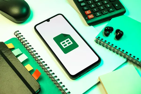 Prag, Çek Cumhuriyeti - 08 18 2025: Merkezde Google Sheets logosunu gösteren bir cep telefonu ile ofis malzemeleri düzenlemesi. Google Sayfalar tablo oluşturmak ve yönetmek için bir platformdur.