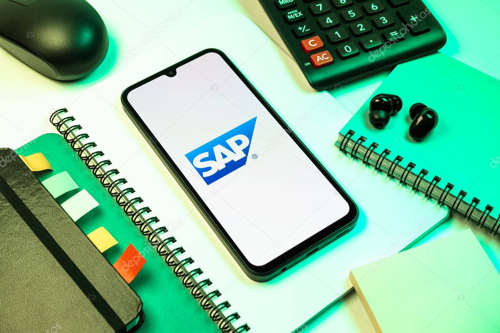 Prague, Czechia - 08 18 2025: An arrangement of office supplies with a mobile phone in the center displaying SAP logo. SAP is a software company providing enterprise applications and solutions.