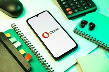 Prag, Çek Cumhuriyeti - 08 18 2025: Opera logosu sergilenen bir cep telefonu ile ofis malzemeleri düzenlemesi. Opera hızlı ve güvenli internet taraması için bir web tarayıcısıdır.