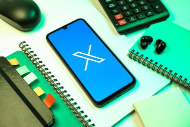 Prag, Çek Cumhuriyeti - 08 18 2025: Merkezinde X logosu sergilenen bir cep telefonu ile ofis malzemeleri düzenlemesi. X, kısa gönderileri ve güncellemeleri paylaşmak için bir platformdur.
