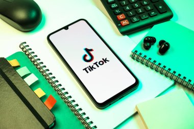 Prag, Çek Cumhuriyeti - 08 18 2025: Merkezde TikTok logosunu gösteren bir cep telefonu ile ofis malzemeleri düzenlemesi. TikTok kısa, yaratıcı ve viral video platformu.