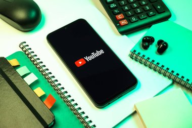 Prag, Çek Cumhuriyeti - 08 18 2025: Merkezde Youtube logosu sergilenen bir cep telefonu ile ofis malzemeleri düzenlemesi. Youtube dünya çapında videoları izlemek ve paylaşmak için bir platform.