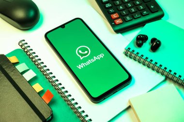 Prag, Çek Cumhuriyeti - 08 18 2025: Ofis malzemelerinin merkezde WhatsApp logosunu gösteren bir cep telefonu ile düzenlenmesi. WhatsApp mesaj, çağrı ve medya göndermek için bir uygulamadır.