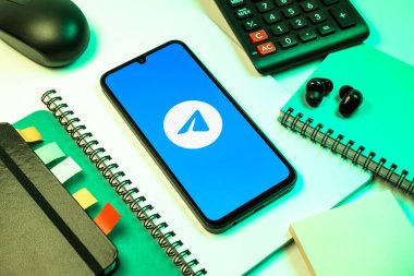 Prag, Çek Cumhuriyeti - 08 18 2025: Merkezde Telegram logosunu gösteren bir cep telefonu ile ofis malzemeleri düzenlemesi. Telgraf hızlı ve güvenli iletiler için bir uygulamadır.