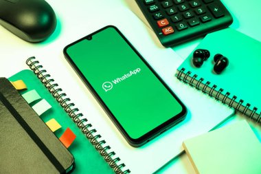 Prag, Çek Cumhuriyeti - 08 18 2025: Ofis malzemelerinin merkezde WhatsApp logosunu gösteren bir cep telefonu ile düzenlenmesi. WhatsApp mesaj, çağrı ve medya göndermek için bir uygulamadır.