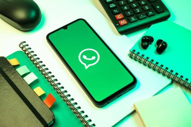 Prag, Çek Cumhuriyeti - 08 18 2025: Ofis malzemelerinin merkezde WhatsApp logosunu gösteren bir cep telefonu ile düzenlenmesi. WhatsApp mesaj, çağrı ve medya göndermek için bir uygulamadır.