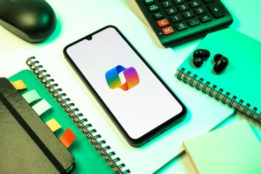 Prag, Çek Cumhuriyeti - 08 18 2025: Merkezde Copilot logosu sergilenen bir cep telefonu ile ofis malzemeleri düzenlemesi. Copilot, üretkenlik yardımı için yazılıma entegre edilmiş bir yapay zeka asistanıdır..