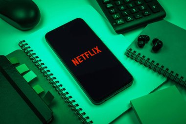 Prag, Çek Cumhuriyeti - 08 18 2025: Merkezde Netflix logosunu gösteren bir cep telefonu ile ofis malzemeleri düzenlemesi. Netflix sinema ve televizyon programları için bir yayın platformudur..