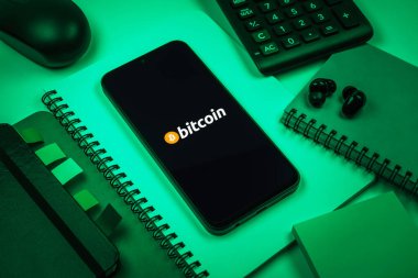 Prag, Çek Cumhuriyeti - 08 18 2025: Merkezde Bitcoin logosu sergilenen bir cep telefonu ile ofis malzemeleri düzenlemesi. Bitcoin merkezi olmayan işlemler için dijital bir kripto para birimidir.