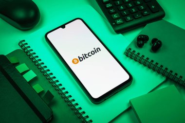 Prag, Çek Cumhuriyeti - 08 18 2025: Merkezde Bitcoin logosu sergilenen bir cep telefonu ile ofis malzemeleri düzenlemesi. Bitcoin merkezi olmayan işlemler için dijital bir kripto para birimidir.