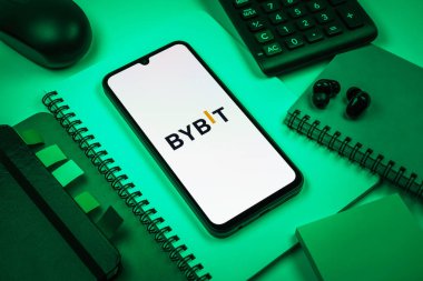 Prag, Çek Cumhuriyeti - 08 18 2025: Merkezde Bybit logosunu gösteren bir cep telefonu ile ofis malzemeleri düzenlemesi. Bybit şifreli para ve türev ticareti için bir platformdur.