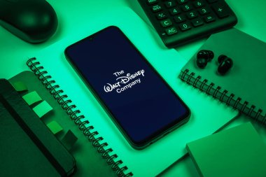 Prag, Çek Cumhuriyeti - 08 18 2025: Merkezde Walt Disney logosunu gösteren bir cep telefonu ile ofis malzemeleri düzenlemesi. Walt Disney film, park ve medya için bir eğlence şirketidir..