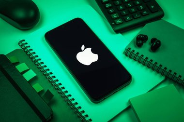 Prag, Çek Cumhuriyeti - 08 18 2025: Merkezi Apple logosunu gösteren bir cep telefonu ile ofis malzemeleri düzenlemesi. Apple iPhone, bilgisayar ve hizmet üreten bir teknoloji şirketidir..