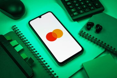 Prag, Çek Cumhuriyeti - 08 18 2025: Merkezde Mastercard logosu sergilenen bir cep telefonu ile ofis malzemeleri düzenlemesi. Mastercard ödeme kartları ve hizmetler sağlayan bir finans şirketidir..