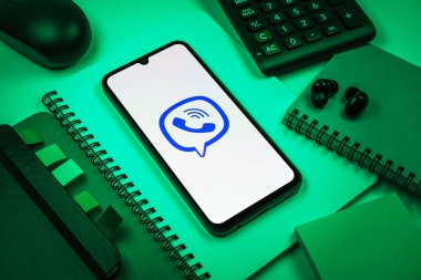 Prag, Çek Cumhuriyeti - 08 18 2025: Merkezde Viber logosunu gösteren bir cep telefonu ile ofis malzemeleri düzenlemesi. Viber aramalar, mesajlar ve medya paylaşımı için bir mesajlaşma uygulamasıdır.