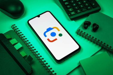 Prag, Çek Cumhuriyeti - 08 18 2025: Merkezde Google Lens logosunu gösteren bir cep telefonu ile ofis malzemeleri düzenlemesi. Google Lens, resimlerdeki görsel arama ve bilgi için kullanılan bir araçtır..