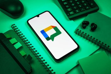 Prag, Çek Cumhuriyeti - 08 18 2025: Merkezde Google Chat logosunu gösteren bir cep telefonu ile ofis malzemeleri düzenlemesi. Google Chat mesajlaşma ve takım işbirliği için bir platformdur.