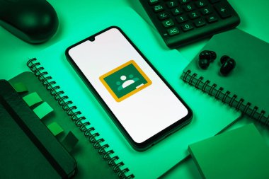 Prag, Çek Cumhuriyeti - 08 18 2025: Merkezde Google Sınıfı logosunu gösteren bir cep telefonu ile ofis malzemeleri düzenlemesi. Google Sınıfı, sınıfları ve eğitim içeriğini yönetmek için bir platformdur.