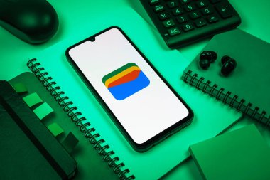 Prag, Çek Cumhuriyeti - 08 18 2025: Merkezde Google Cüzdan logosunu gösteren bir cep telefonu ile ofis malzemeleri düzenlemesi. Google Cüzdanı dijital ödeme yöntemlerini depolamak ve kullanmak için bir platformdur.