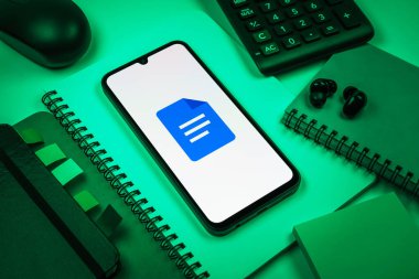 Prag, Çek Cumhuriyeti - 08 18 2025: Merkezde Google Docs logosunu gösteren bir cep telefonu ile ofis malzemeleri düzenlemesi. Google Docs metin belgeleri oluşturmak ve düzenlemek için bir platformdur.