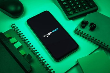 Prag, Çek Cumhuriyeti - 08 18 2025: Merkezde Amazon Müzik logosu sergilenen bir cep telefonu ile ofis malzemeleri düzenlemesi. Amazon Müzik müzik müzik için bir platformdur..