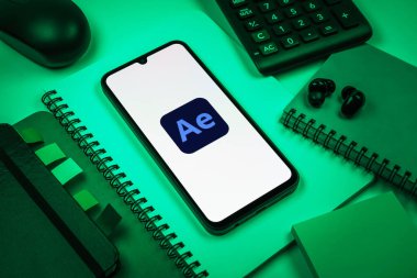 Prag, Çek Cumhuriyeti - 08 18 2025: Ofis malzemelerinin merkezde After Effects logosu sergilenen bir cep telefonu ile düzenlenmesi. After Effects hareket grafikleri ve görsel efektler için bir yazılımdır..