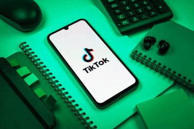 Prag, Çek Cumhuriyeti - 08 18 2025: Merkezde TikTok logosunu gösteren bir cep telefonu ile ofis malzemeleri düzenlemesi. TikTok kısa, yaratıcı ve viral video platformu.