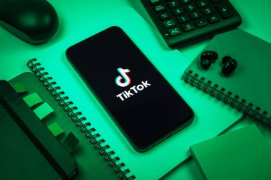 Prag, Çek Cumhuriyeti - 08 18 2025: Merkezde TikTok logosunu gösteren bir cep telefonu ile ofis malzemeleri düzenlemesi. TikTok kısa, yaratıcı ve viral video platformu.
